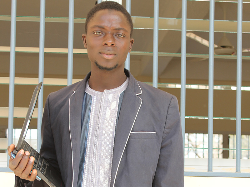 Student standing holding a laptop